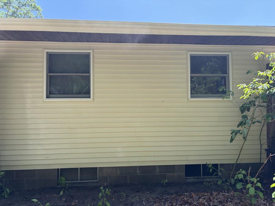 Clean, bright house siding wall with two windows after pressure washing