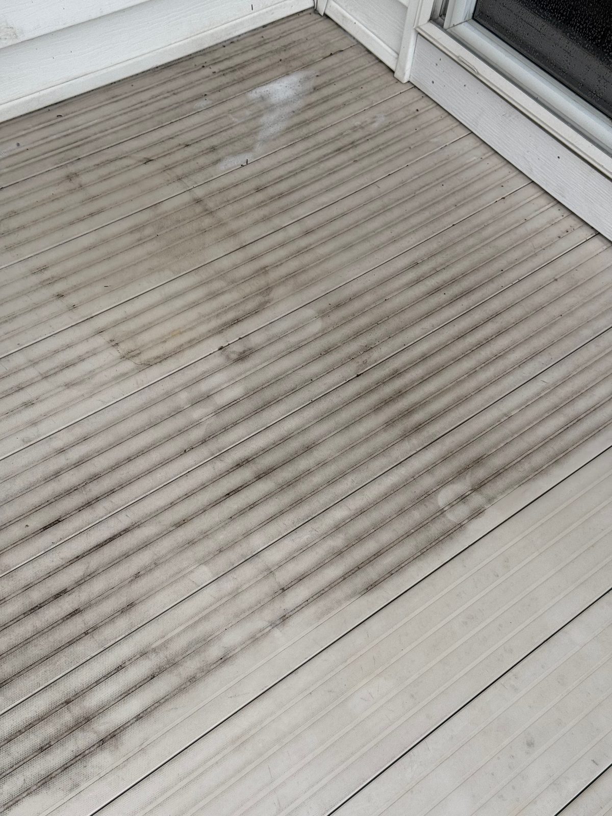 Weathered composite deck with algae and mildew buildup before pressure washing